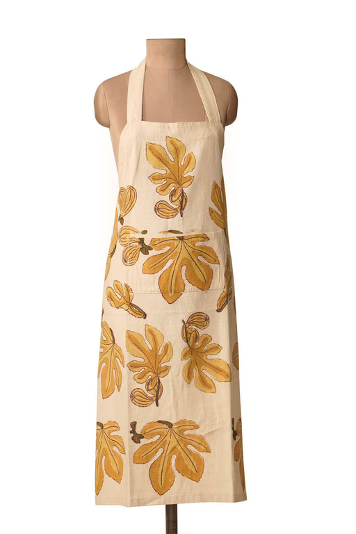 Couleur Nature - Fig Citrine Apron: Cream apron with stylized yellow-orange fig leaves and fruit, halter neck strap, and front patch pocket, ideal for kitchen use.