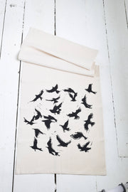 Hearth and Harrow - Organic Cotton Flying Crows Tea Towel featuring black bird silhouettes, designed and hand-printed with eco-friendly ink, laid on a wooden surface.