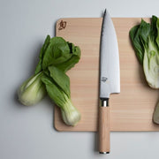 Shun Classic Chef's Blonde, 8 inches, knife on light-wood cutting board with baby bok choy, showcasing its versatile blade and ergonomic handle for culinary tasks.