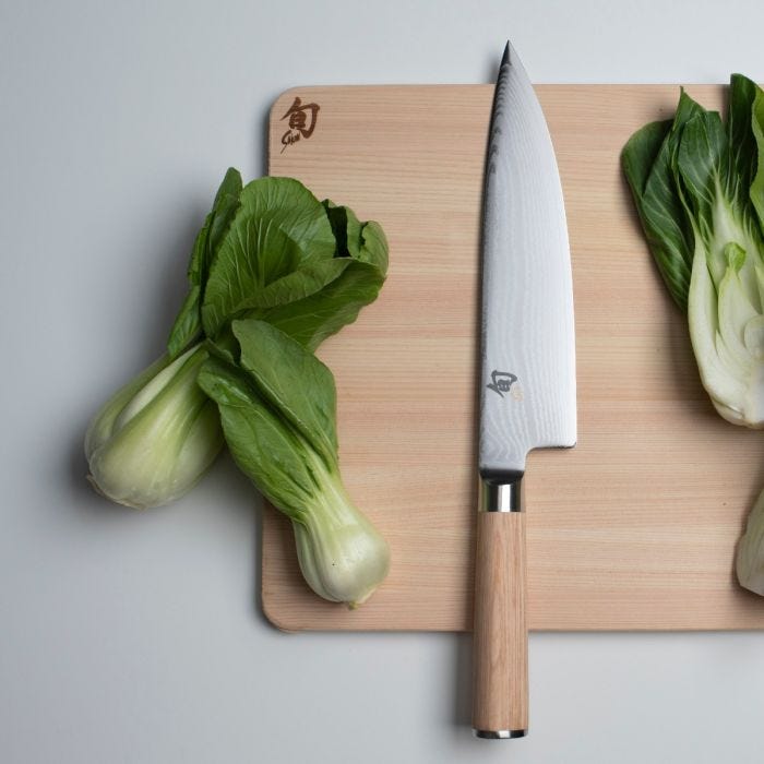 Shun Classic Chef's Blonde, 8 inches, knife on light-wood cutting board with baby bok choy, showcasing its versatile blade and ergonomic handle for culinary tasks.