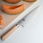 Shun Classic Chef's Blonde 8-in. Knife on board with cantaloupe slices, showcasing its precision and versatility for preparing fruits and more.