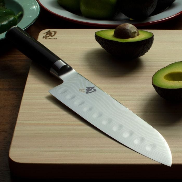 Shun Classic Hollow Ground Santoku, 7 inches, resting on Himoki cutting board with avocados, showcasing its precision and versatility for kitchen prep at Athens Cooks.