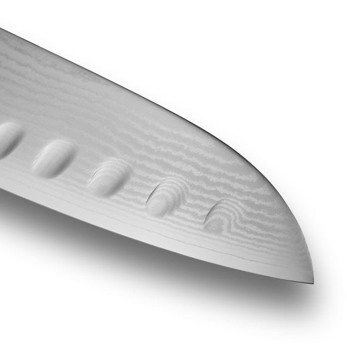 Close-up of a 7-inch Shun Classic Hollow Ground Santoku knife blade, showcasing its Damascus steel pattern and scalloped indentations for efficient cutting.