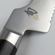 Close-up of the Shun Classic Offset Bread Knife, showcasing the scalloped spine, etched logo with kanji Gin, and bolstered heel against a neutral background.