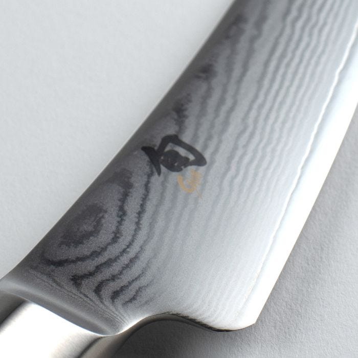 Shun | Classic Boning & Fillet knife close-up, showcasing its 6-inch Damascus steel blade with wood-grain pattern and Japanese logo, ideal for precise meat and fish preparation.