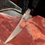 Shun | Classic Boning & Fillet, 6 inches: A gloved hand trims beef with a sharp, narrow Shun knife, ideal for precise meat and fish preparation.
