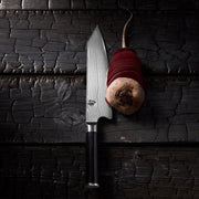 Shun Classic Kiritsuke 8-inch knife with Damascus pattern and dark handle on wood surface, slicing thin beet rounds, showcasing precision and versatility for expert chefs.