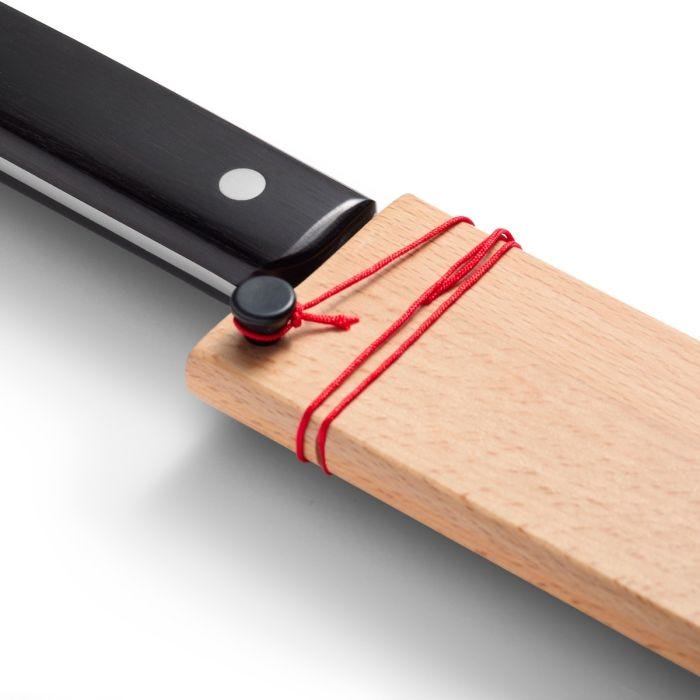 Shun Classic Hollow Ground Brisket Knife with black handle rests in a wooden sheath, secured by red cord, ideal for slicing meats.
