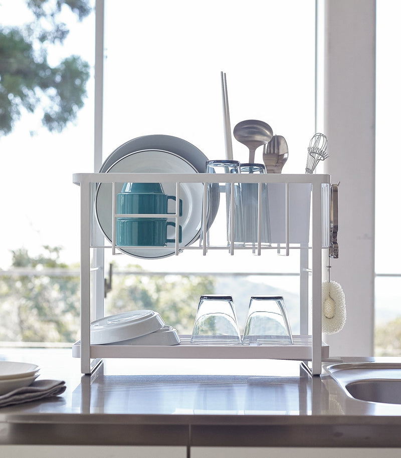 Yamazaki Home | Two-Tier Dish Rack - White, features a compact design with a versatile, adjustable plastic drainer tray and utensil holder for efficient kitchen space use.