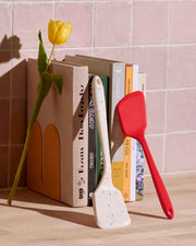 GIR | Mini Flip - Teal spatula rests atop a cookbook, highlighting its versatility for cooking tasks in your kitchen.