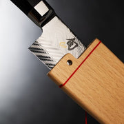 Shun Dual Core Kiritsuke, 8 inches: Close-up of Damascus-pattern blade with maker’s mark, partially sheathed in wooden saya, featuring an octagonal black handle.