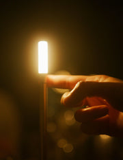 Finger pointing at VANMOKUM | GRAYPANTS Wick Portable Rechargeable Lamp, highlighting its candle-like ambiance and utility, perfect for creating gatherings and shared moments.