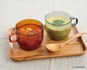HARIO USA - HARIO Colors Glass Stackable Mug, 300ml: Grey, shown holding vibrant soups, exemplifies practical, stylish heatproof glassware for culinary enthusiasts.