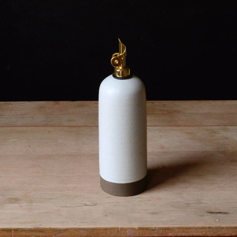 Rose Line Pottery - Oil Bottle - White - 22 Ounces, features a gold-plated lighter mechanism atop a handcrafted ceramic vessel with a raw-clay base, ideal for oils and syrups.