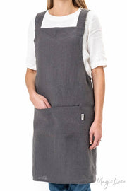 Person wearing MagicLinen's pinafore cross-back linen apron, showcasing its twin-sectioned front pocket and unisex design, ideal for cooking and gardening.