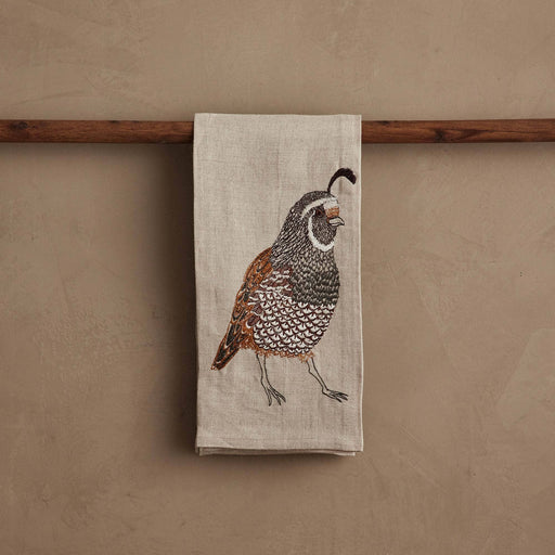 Coral & Tusk - Quail Tea Towel, featuring detailed quail embroidery on natural linen, draped over a wooden rod, ideal for sophisticated kitchen decor.