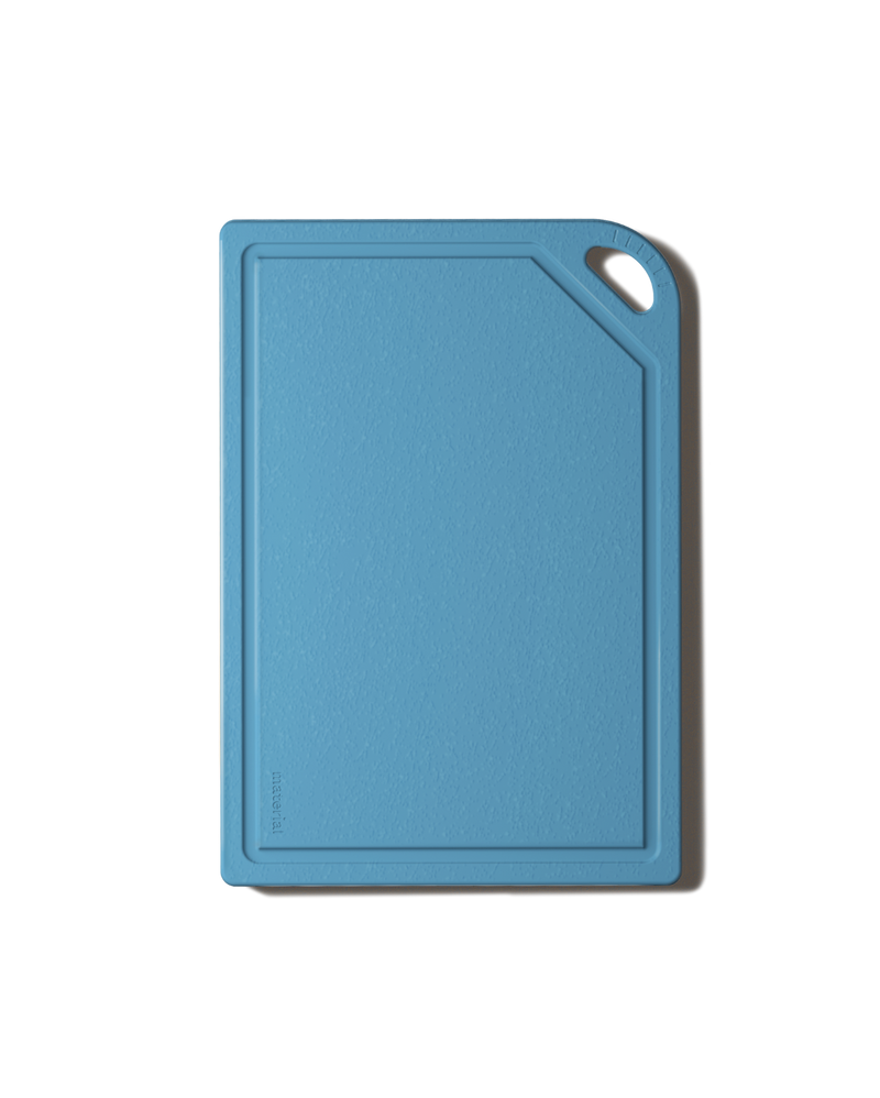 The MK Free Board: Ocean, a sky-blue kitchen cutting board with a textured surface, raised edges, and a corner handle for easy use and storage.