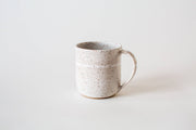 RachaelPots - 12 Oz Original Mug: Sage, a speckled off-white ceramic mug with a rounded handle and thumb rest, hand-thrown for a unique, artisanal touch.