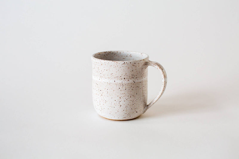 RachaelPots - 12 Oz Original Mug: Sage, a speckled off-white ceramic mug with a rounded handle and thumb rest, hand-thrown for a unique, artisanal touch.