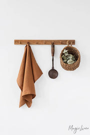 Linen tea towel with a hanging loop displayed with a potted plant, highlighting its absorbency and durability for versatile kitchen use.