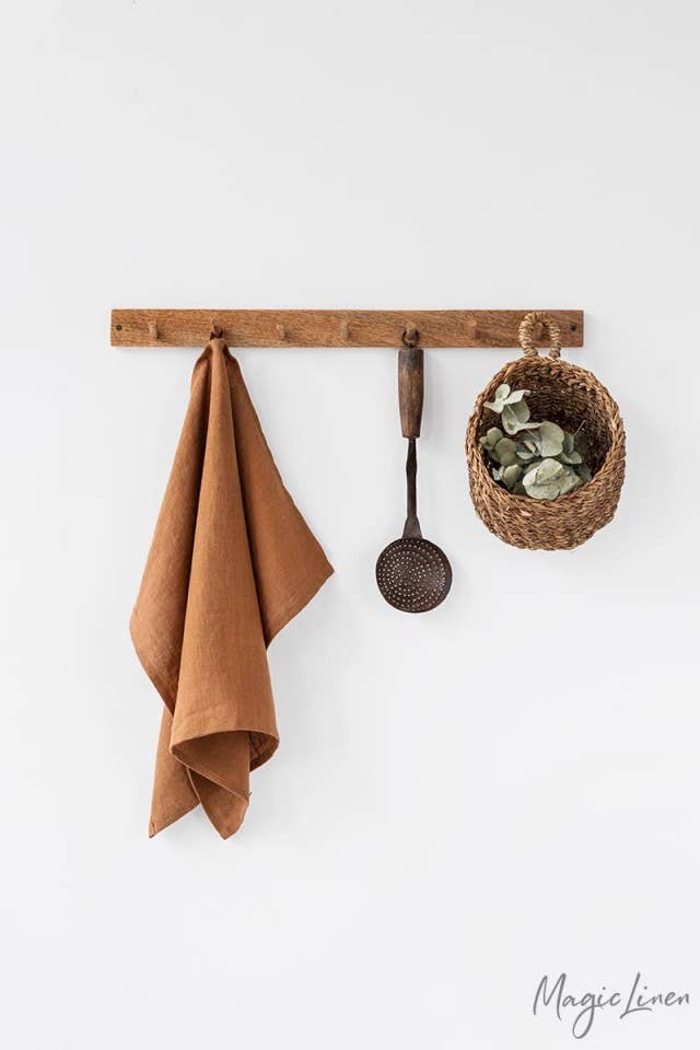 Linen tea towel with a hanging loop displayed with a potted plant, highlighting its absorbency and durability for versatile kitchen use.