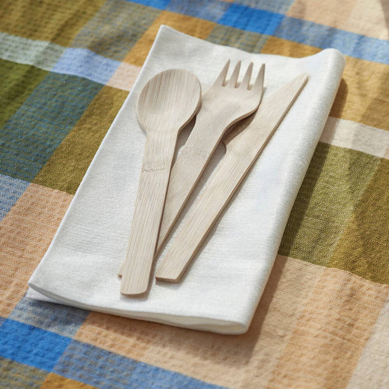 Veneerware® Bamboo Knife, Fork, and Spoon Set on a checkered tablecloth, showcasing eco-friendly, compostable utensils ideal for sustainable dining, available at Athens Cooks.