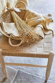 Wicker basket on chair with linen tea towel by MagicLinen, featuring absorbent European flax fabric, perfect for kitchen tasks. Available in Moss Yellow.