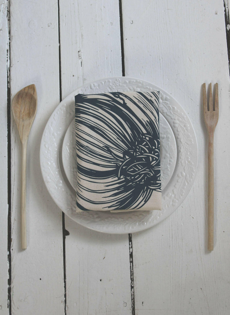 Hearth and Harrow | Organic Cotton Garlic Tea Towel, elegantly screen printed, displayed folded on a plate, showcasing its unique garlic design and sustainable craftsmanship.