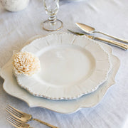 Bella Bianca Beaded Dinner Plate on a table with silverware, featuring intricate beaded patterns, made of durable Italian stoneware, ideal for elegant dining.