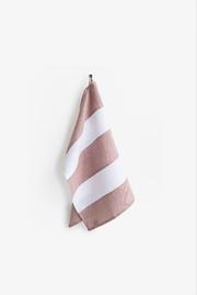 Striped linen tea towel hanging on a hook, featuring a loop for easy storage. Part of MagicLinen's zero-waste program, made from soft, absorbent European flax.