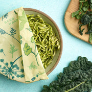 Bee's Wrap - Assorted 3 Pack - Herb Garden, Plant Based Wax, shown with noodles and herbs, ideal for preserving food sustainably.