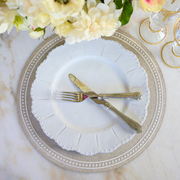 Bella Bianca Beaded Dinner Plate by Arte Italica, featuring Italian stoneware with elegant beaded patterns, displayed with silverware on a dining table setting.