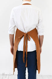 Person wearing the MagicLinen men's linen apron with a pocket, featuring comfortable back straps and an adjustable front grommet, ideal for cooking or grilling.