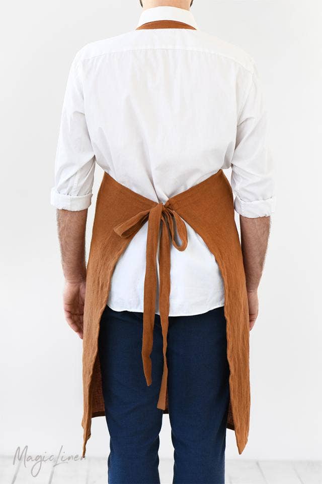Person wearing the MagicLinen men's linen apron with a pocket, featuring comfortable back straps and an adjustable front grommet, ideal for cooking or grilling.