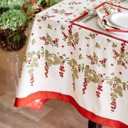 Couleur Nature - Gooseberry Red & Green tablecloth with leaf and berry motif on a dining table, complemented by elegant place settings and a matching decorative vase.