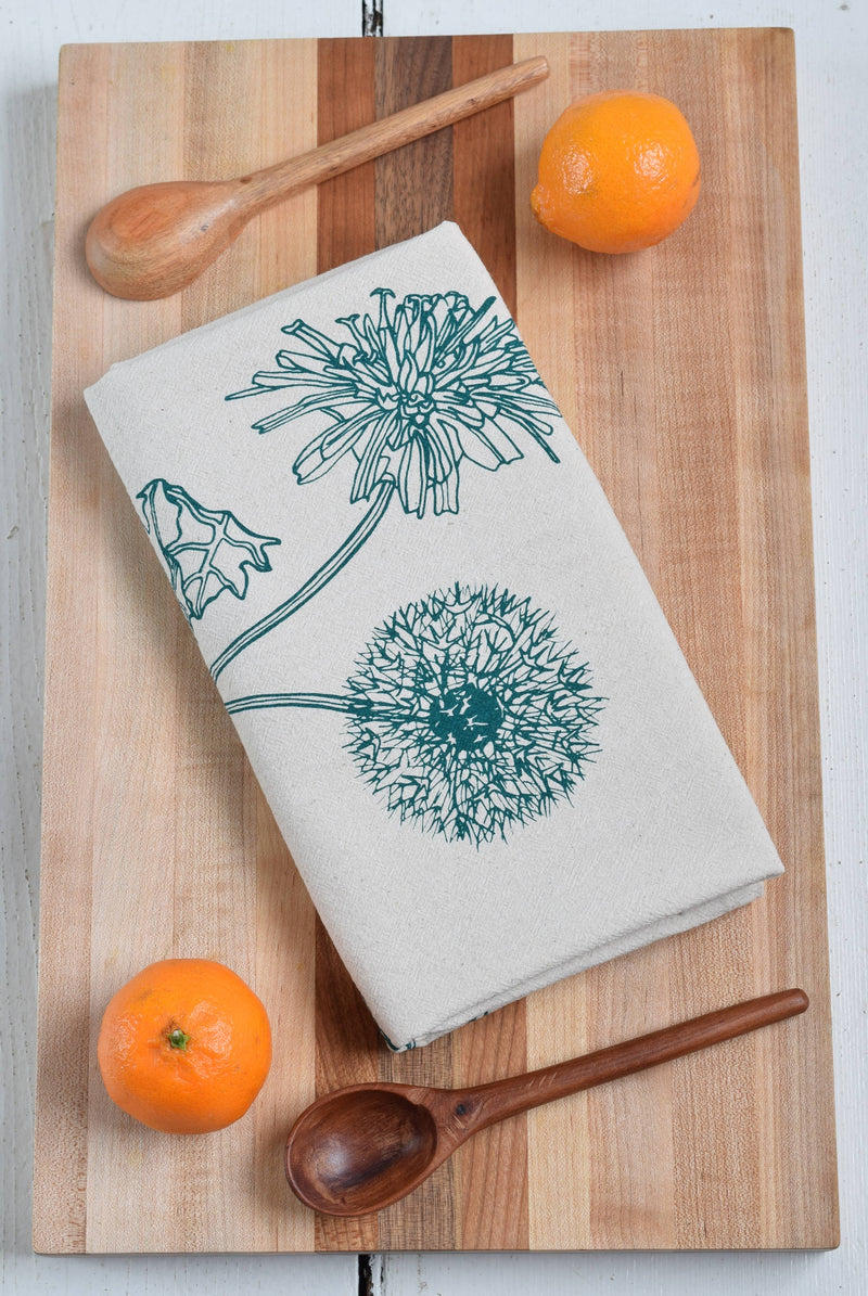 Hearth and Harrow - Organic Cotton Dandelion Tea Towel in green, displayed on a wooden board, featuring a botanical print and eco-friendly design.