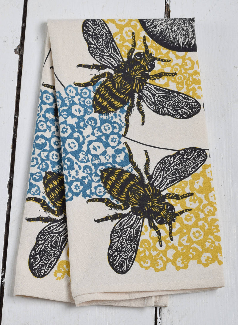 Hearth and Harrow - Honeybee Tea Towel - Organic Cotton - Oversized 30 x 30, featuring stylized bees on floral patterns, folded on a white wooden surface.