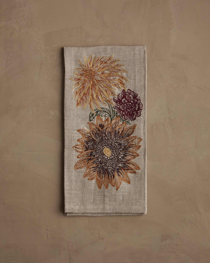 Coral & Tusk - Autumn Sunflower Tea Towel: A folded linen tea towel with embroidered sunflowers and a burgundy mum, showcasing autumnal hues.