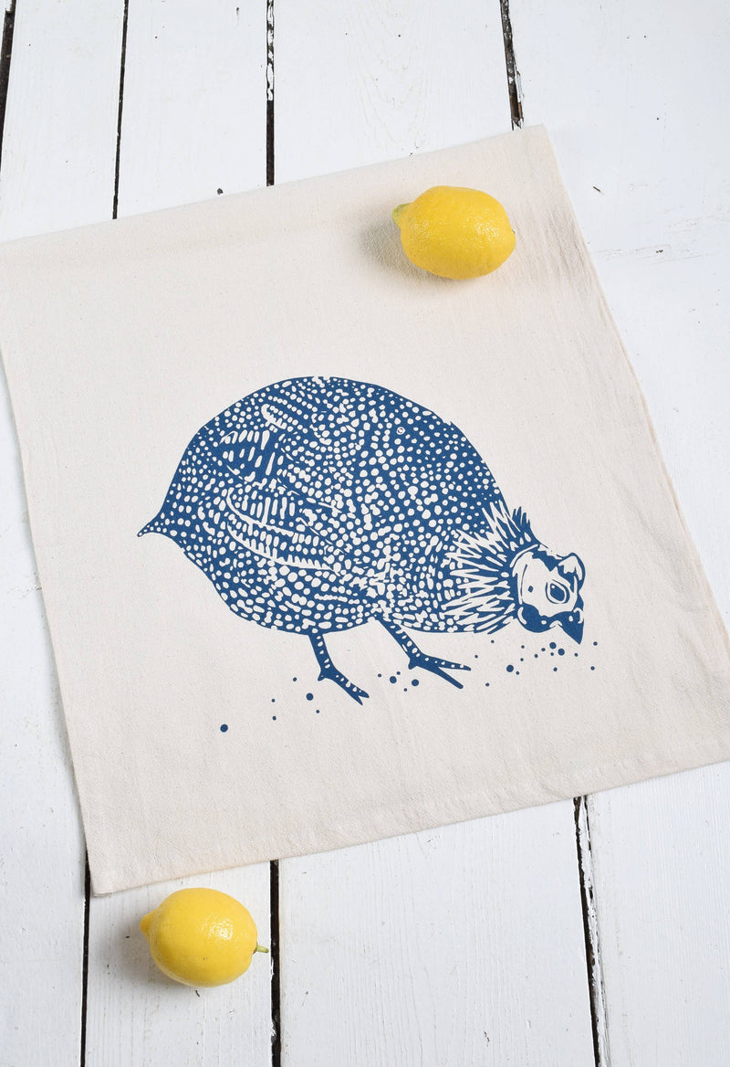 Hearth and Harrow - Organic Cotton Guinea Hen Tea Towel in Navy Blue displayed with lemons, showcasing the handprinted guinea fowl design on a white surface.