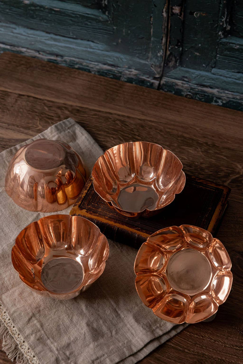 Vintage-inspired copper fluted bowls with crown engravings, displayed on a rustic tabletop, showcasing their elegant design and versatile use for entertaining.