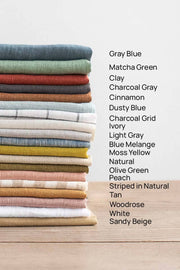 MagicLinen Charcoal Grey Linen Bib Apron with Pockets, showcasing a stack of colorful fabric; ideal for cooking and gardening.