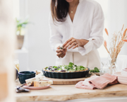 Person garnishing a savory tart, highlighting Emile Henry Modern Classics Loaf Pan, Rouge, 9 x 5, in a cozy kitchen setting, emphasizing elegance and durability.