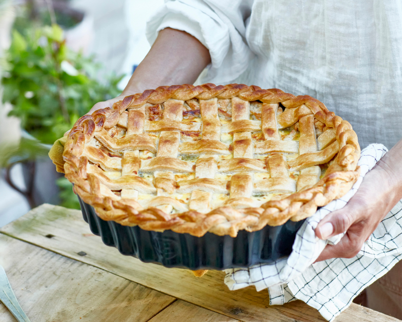 Person holding Emile Henry Modern Classics Mini Pie Dish with lattice-topped pie, showcasing the bakeware's craftsmanship and perfect individual serving size.