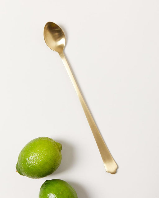 Farmhouse Pottery | Essex Barware, Long Spoon - Brushed Gold, displayed with two limes, ideal for mixing cocktails, combining elegance and functionality for any bar setting.