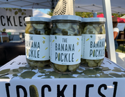 PICKLES by Evergreen and Market - The Banana Pickle jars displayed at a market stall, showcasing sweet, spicy, and sour pickled banana slices in brine.