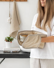 Woman holding MagicLinen double oven mitt: Natural Gingham, designed to protect hands from heat, part of Athens Cooks' zero-waste kitchen accessory collection.