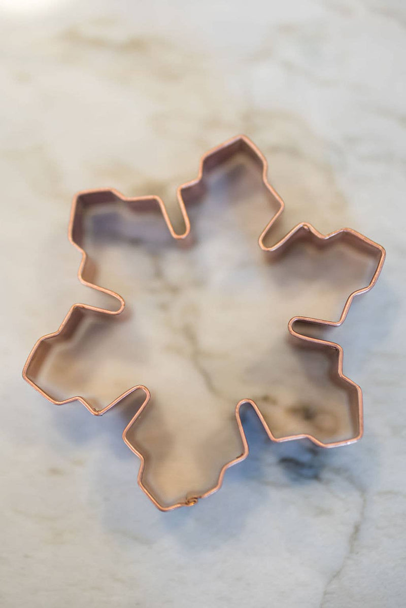 Galley and Fen - Christmas Cookie Cutters - Set of 6, featuring a snowflake-shaped copper cutter on a marble countertop, ideal for festive baking.
