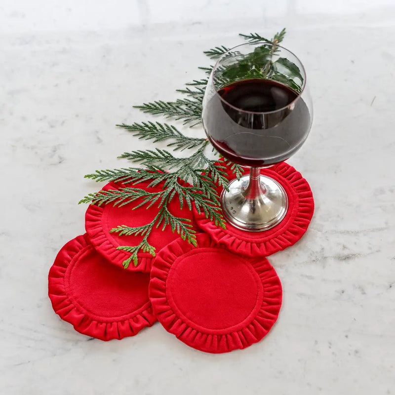 Round Ruffle Velvet Coaster Set by Arte Italica & Crown Linen Designs, featuring four elegant coasters with a wine glass and evergreen sprig on a marble surface.