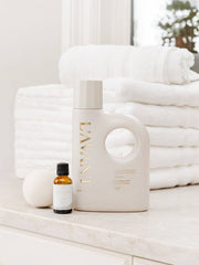 L'AVANT Collective - Laundry Detergent Fresh Linen on a marble countertop with an amber bottle and wool dryer ball, highlighting its eco-friendly, gentle yet effective cleaning formula.