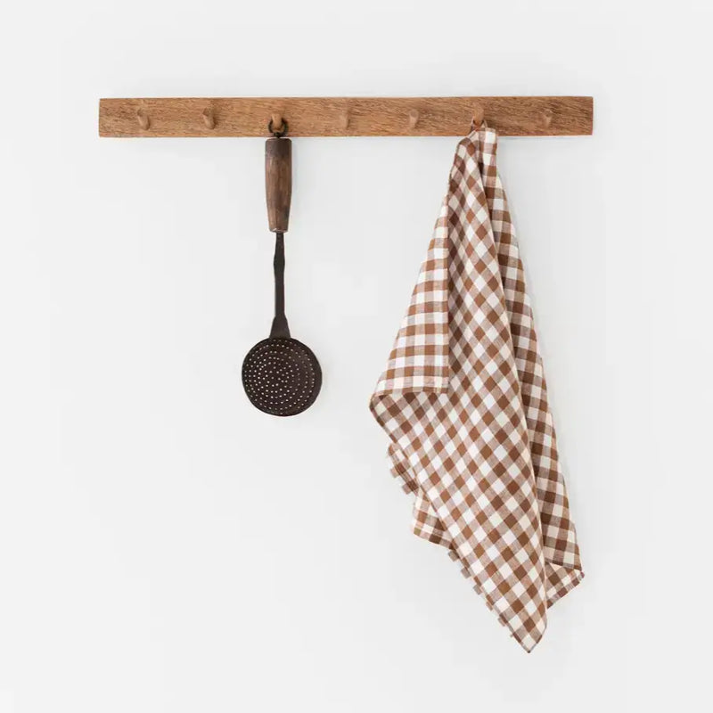 Linen tea towel on rack, featuring a brown and white checkered pattern, made from durable European linen. Perfect for kitchen tasks.
